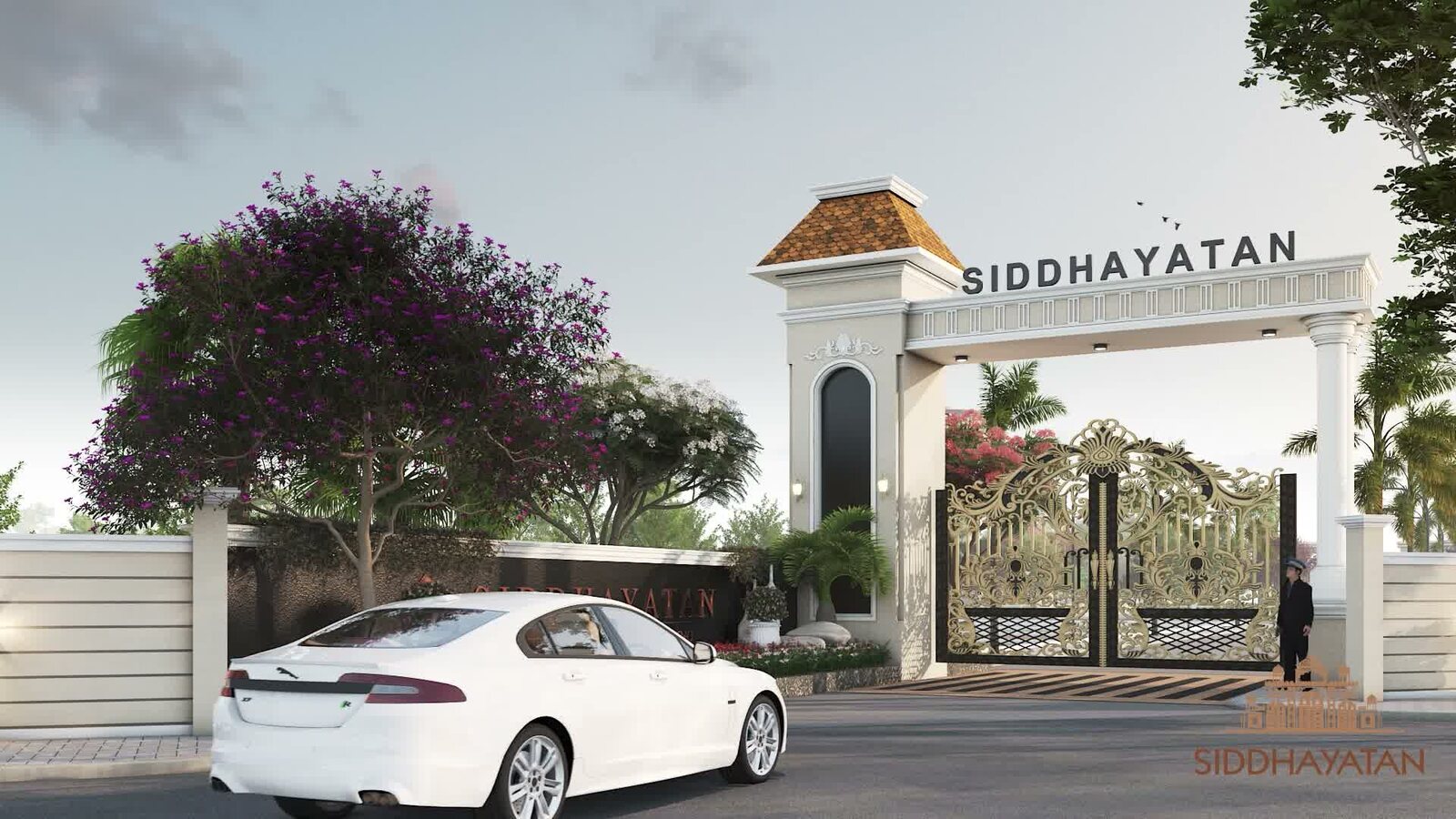 The gated entrance archway at Siddhayatan in Manglia, with a flowering tree and landscaped boundary wall along the approach road
